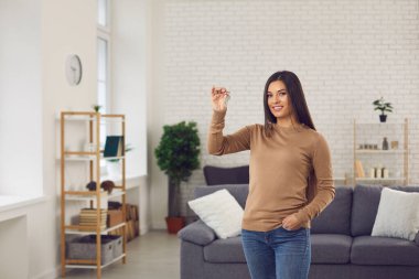 Yeni güzel dairesinde duran ve anahtarlarını gösteren mutlu bekar bir kadın.