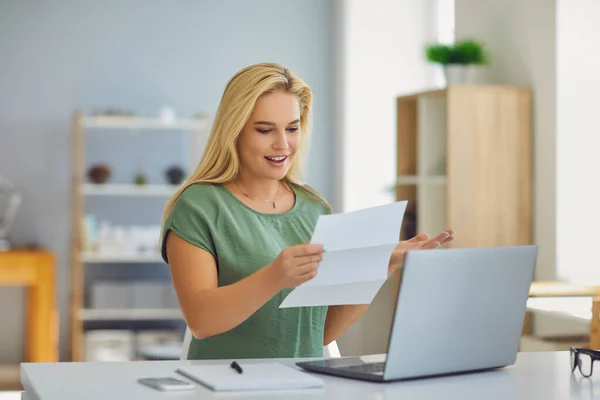Šťastná mladá žena sedí doma a čte si oficiální dopis s dobrou zprávou — Stock fotografie