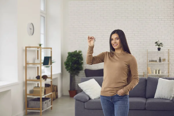 Šťastná svobodná mladá žena stojící ve svém novém krásném bytě a ukazující klíče — Stock fotografie