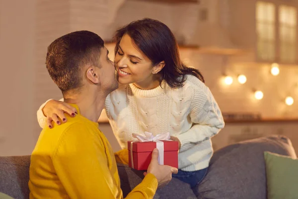 Pareja sonriente dando regalos y besándose en casa durante el día de San Valentín celebrando — Foto de Stock