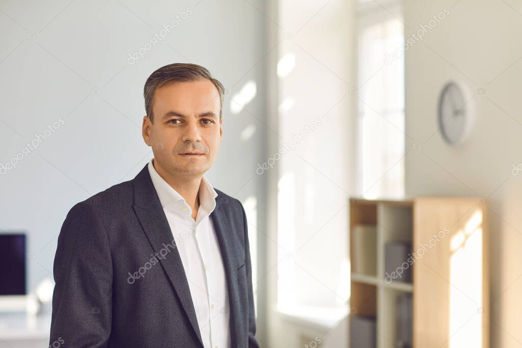 Businessman, company executive manager or CEO looking at camera standing in sunny office
