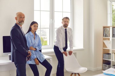 Muhtelif profesyonel iş adamları ofiste durup kameraya bakıyorlar..