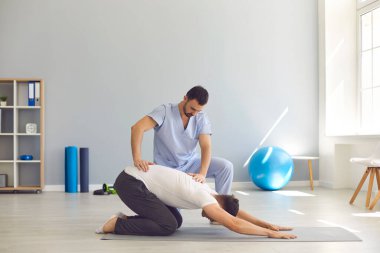 Erkek doktor osteopath spor yaparken ellerini kullanarak erkekleri iyileştiriyor.
