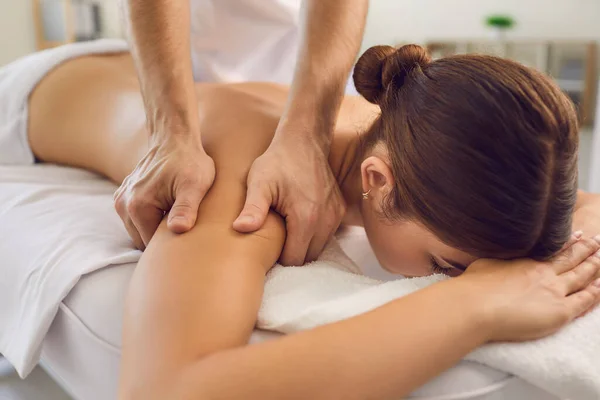 Händer massör gör avkopplande massage av rygg och armar för liggande kvinna — Stockfoto