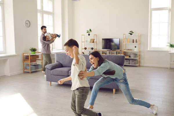 Szczęśliwa rodzina ciesząca się wolnym czasem, grająca w berka i biegająca jak szalona w salonie — Zdjęcie stockowe