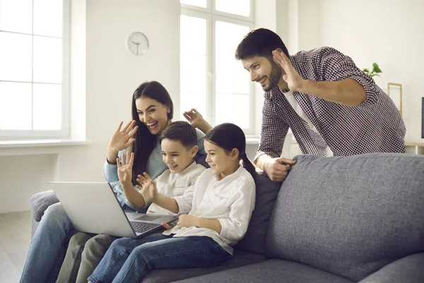 Счастливая семья с маленькими детьми видеосвязь с родственниками и размахивание руками у ноутбука — стоковое фото