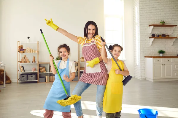 Glad ung mor och små barn har roligt samtidigt städa upp lägenheten tillsammans — Stockfoto