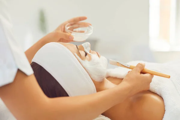 Professionele cosmetoloog brengt een wellness hydraterende crème aan op een vrouwengezicht in de spa. — Stockfoto