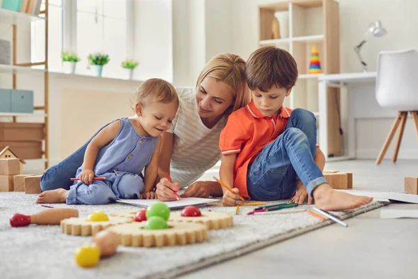 Happy smiling woman mother and children drawing together with pencils at home — Stock Photo, Image