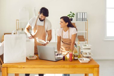 Yiyecek dağıtım servisi çalışanları, paket servis siparişlerini paket kâğıt poşetlere dolduruyorlar.