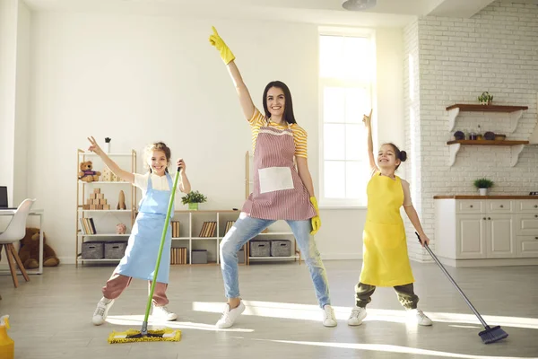 Bambini felici e giovane madre che ballano e si divertono mentre puliscono il pavimento — Foto Stock