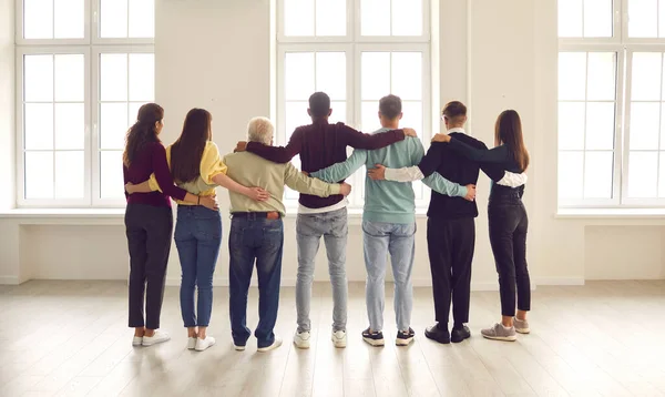 Grupo de apoio confiante diversas pessoas olhando pela janela, de pé todos juntos e abraçando — Fotografia de Stock