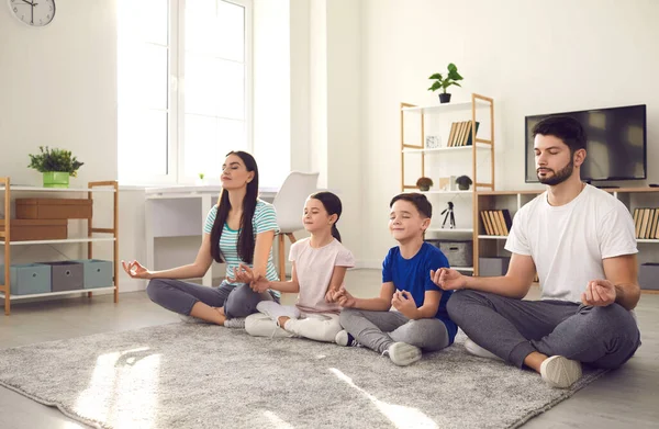 Felice giovane famiglia con bambini piccoli facendo yoga e praticando la meditazione insieme — Foto Stock