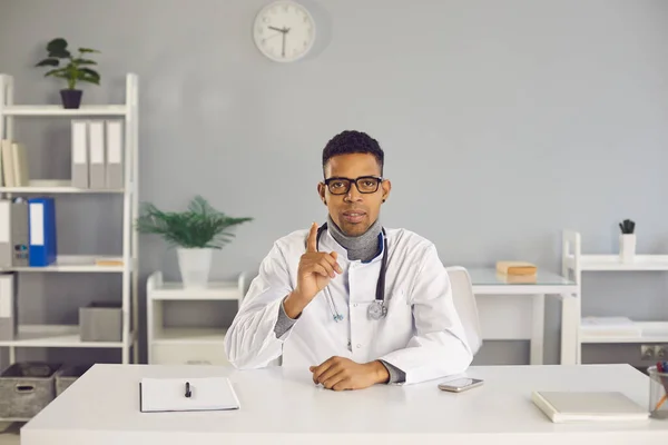 Arzt sitzt am Schreibtisch, erzählt über Behandlung und gibt Gesundheitsempfehlungen — Stockfoto