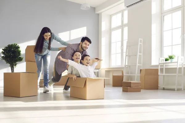 Emocionados padres e hijos jugando con cajas de cartón en su casa recién comprada — Foto de Stock