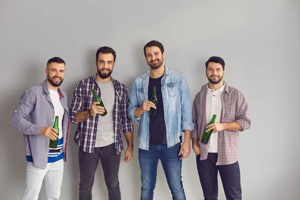 Groep gelukkige vrienden die in de studio staan, bier vasthouden, glimlachen en naar de camera kijken — Stockfoto