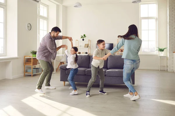 Gelukkige ouders en kinderen dansen en plezier hebben in de woonkamer van een nieuw appartement — Stockfoto