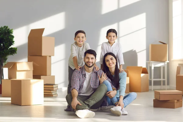 Portret van een gelukkig jong gezin met kleine kinderen op de vloer in een nieuw huis — Stockfoto