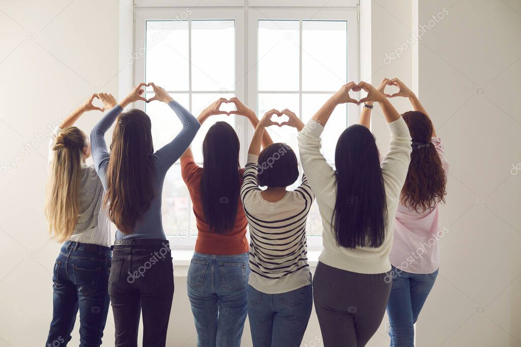 Group of women standing together and doing heart shaped gesture with their hands