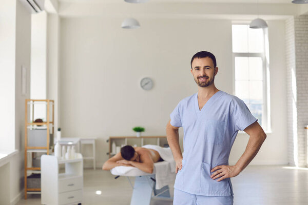 Молодой, уверенный в себе мужчина, профессиональный хиропрактик стоя и глядя в камеру