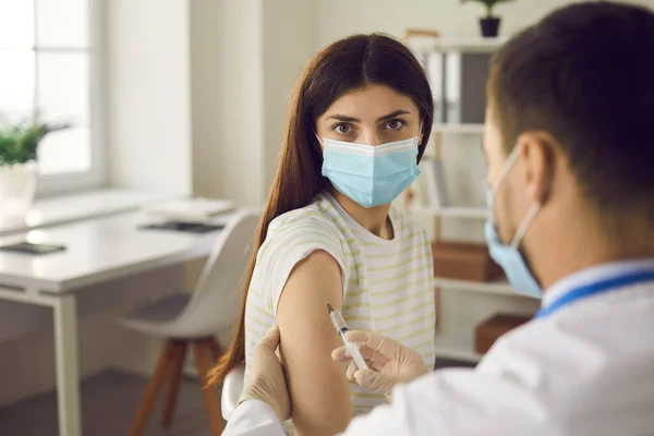 Woman patient in medical face looking at camera while getting vaccination — Stock Photo, Image