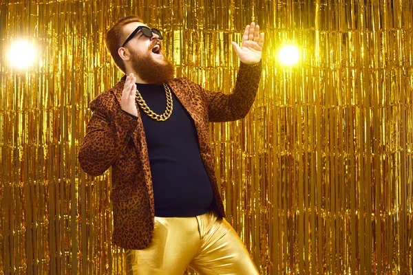Feliz showman barbudo cantando, dançando e se divertindo no palco com fundo dourado — Fotografia de Stock
