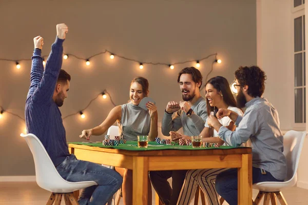Young happy friends playing board games on table at home and having fun