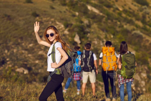 Usmívající se dívka turistické turistka s batohem stojící a mává rukou při turistice — Stock fotografie