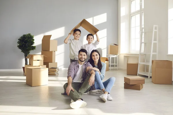 Porträtt av leende mor, far och barn i sitt nya hus på flyttdagen — Stockfoto