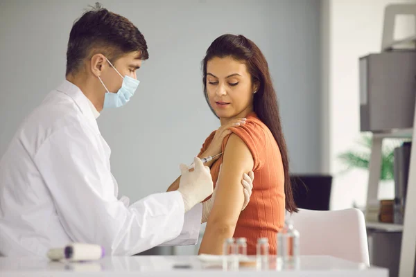 Homme médecin en uniforme blanc et masque médical faisant injection de coronavirus pour femme — Photo