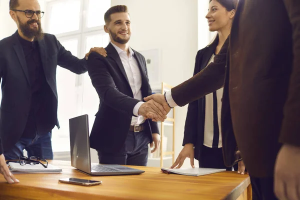 Giovani partner commerciali sorridenti che si stringono la mano dopo i negoziati di successo in carica — Foto Stock