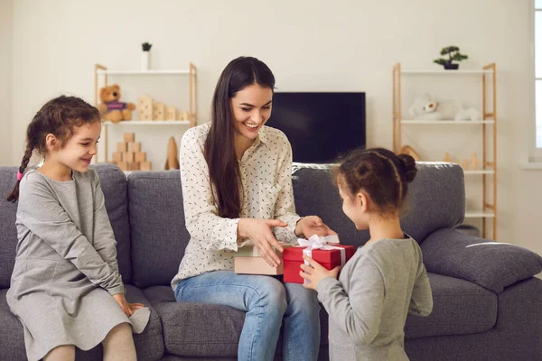 Joyeux jeune mère obtenir des cadeaux de vacances dans des boîtes de fête de ses filles — Photo