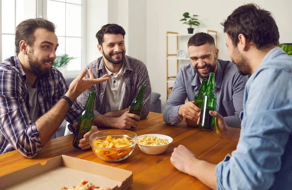 Groep glimlachende mannen vrienden zittend met berenflesjes en snacks en kletsen — Stockfoto