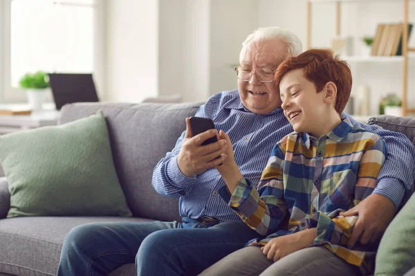 Petit-fils montrant à grand-père comment utiliser les médias sociaux ou faire un appel vidéo sur un téléphone mobile — Photo