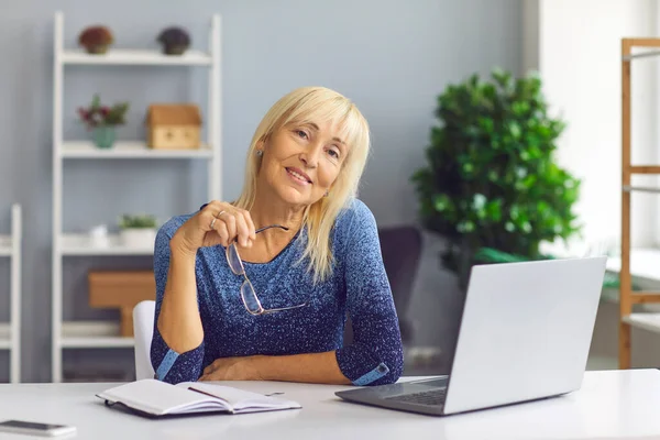 Pozitivní žena středního věku pracovník sedí v kanceláři při pohledu do kamery během pracovního dne — Stock fotografie