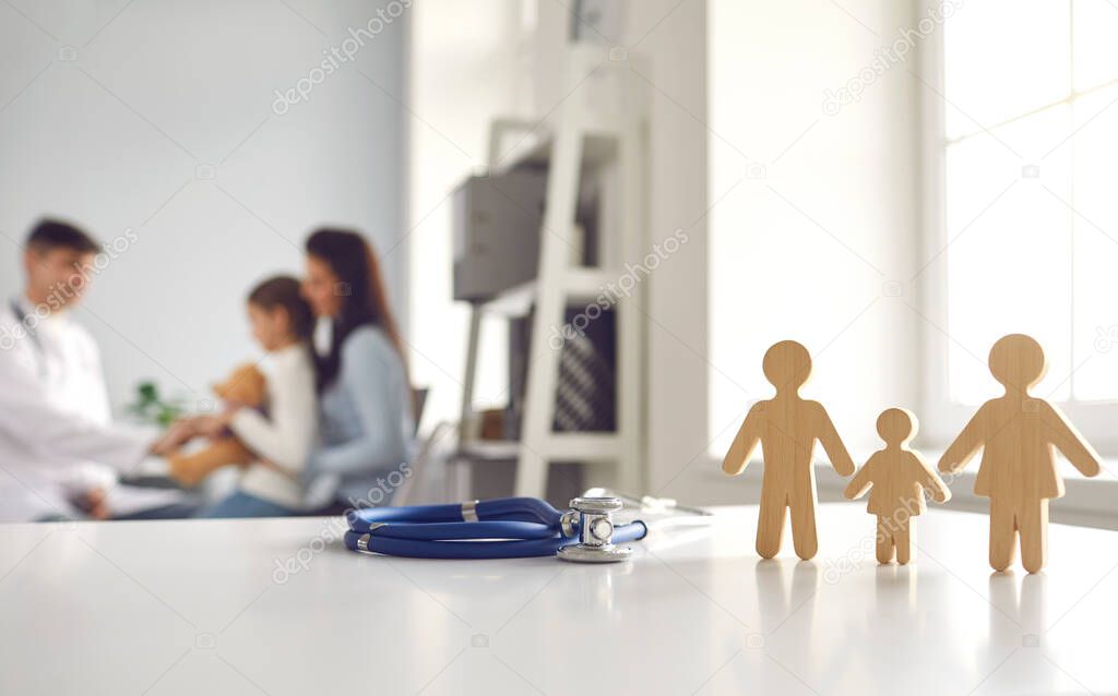 Blurred background with small family member figures on doctors table at the clinic