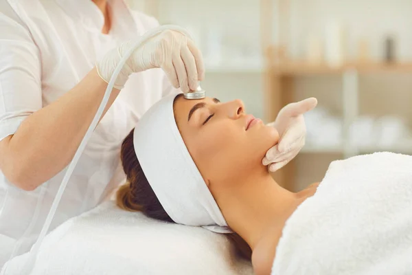 Mujer que recibe cavitación por ultrasonido de la piel facial y cosméticos antienvejecimiento del cosmetólogo — Foto de Stock