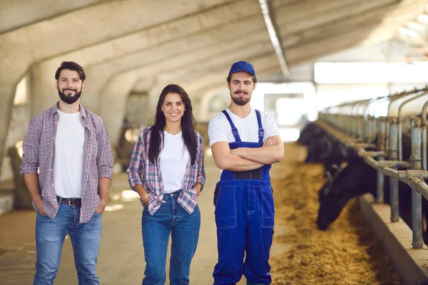 Retrato de un par de jóvenes agricultores junto con un campesino en un establo. —  Fotos de Stock