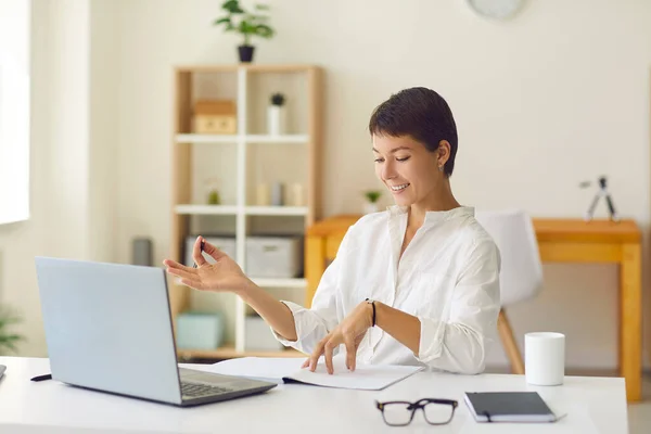 Usmívající se trenér s online lekci se studentem nebo hosting webinář sedí za stolem s notebookem — Stock fotografie