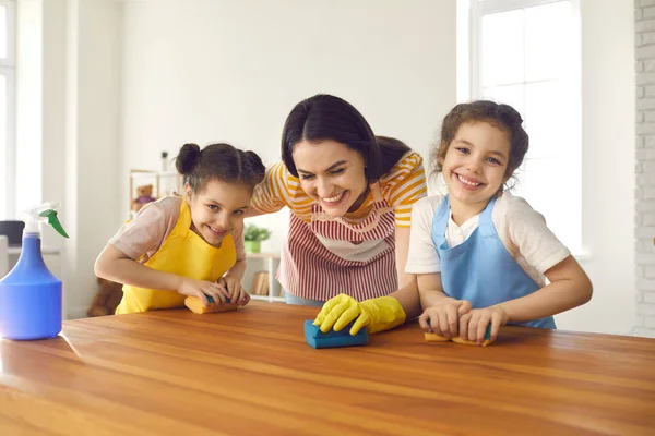 Nette kleine Töchter lernen Familienarbeit und helfen der Mutter, den Tisch zu waschen — Stockfoto
