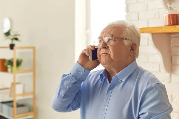 Oudere man probeert zich iets te herinneren of denkt wat te zeggen terwijl hij telefoneert. — Stockfoto