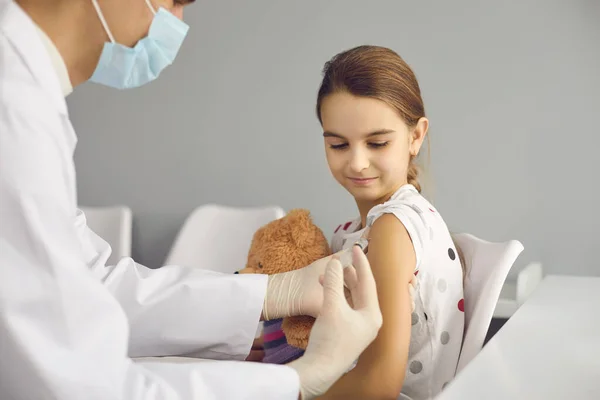 Lachende meisjespatiënt zittend en vaccinatie met injectiespuit tegen coronavirus — Stockfoto
