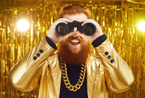 Feliz homem engraçado em uma roupa funky com uma cadeia de ouro enorme olhando através de binóculos — Fotografia de Stock