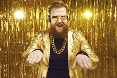 Parlak altın ceketli DJ, kulaklıklar ve gece kulübünde müzik çalan havalı güneş gözlükleri.