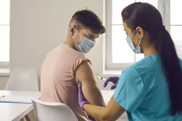 Enfermeira que administra vacina contra a gripe a doentes jovens durante a campanha de vacinação sazonal — Fotografia de Stock