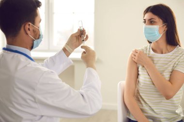 Doktor, klinikte aşı kampanyası sırasında aşıyla şırınga hazırlıyor.