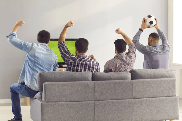 Fyra upphetsade män vänner sitter på soffan och tittar på känslomässigt fotboll match — Stockfoto