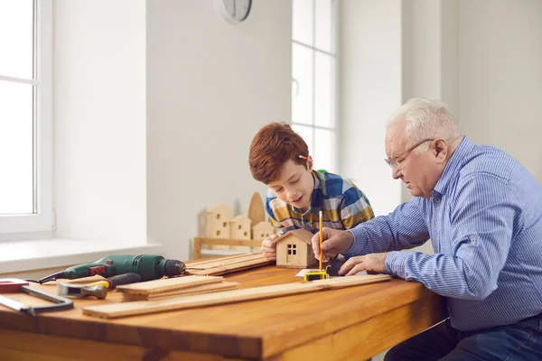 爷爷和他的小孙子在木工车间做木制玩具屋 — 图库照片