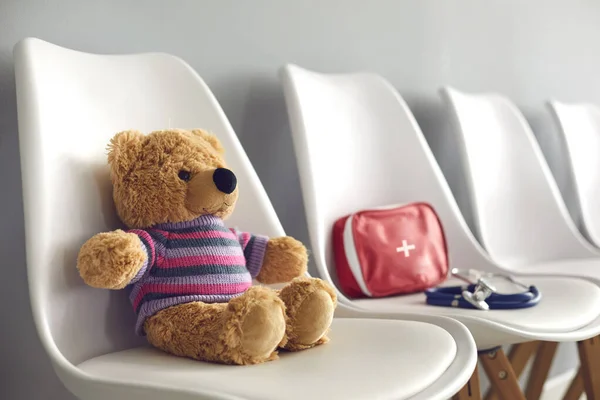 EHBO-kit, stethoscoop en schattige teddy in wachtkamer van kinderziekenhuis — Stockfoto