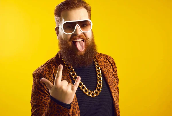 Engraçado excêntrico barbudo homem em roupa extravagante fazendo chifre sinal e furar a língua para fora — Fotografia de Stock